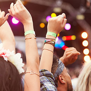 Crowd Raising Hands While Watching Concert - Lead Image for Festivals Page